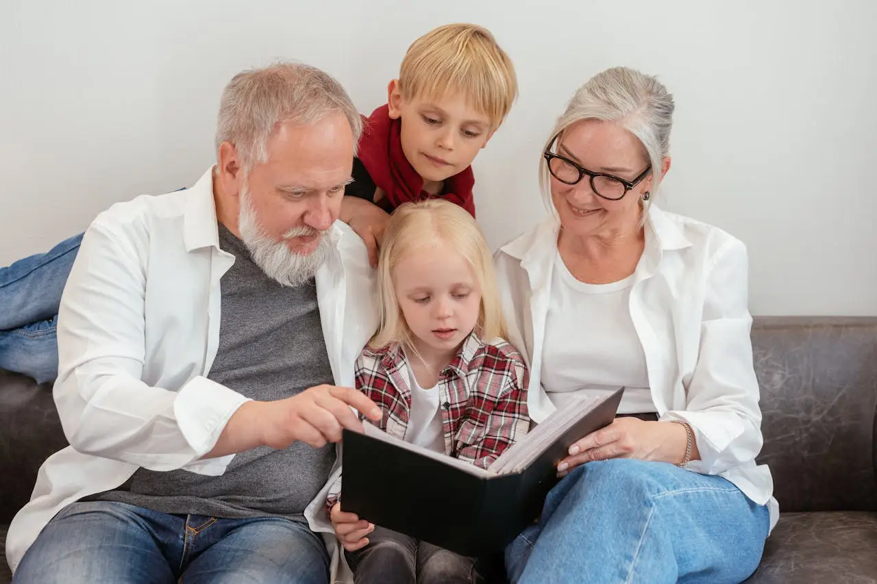 An older couple and a child are seated on a couch, focused on reading a book, enjoying a cozy family moment