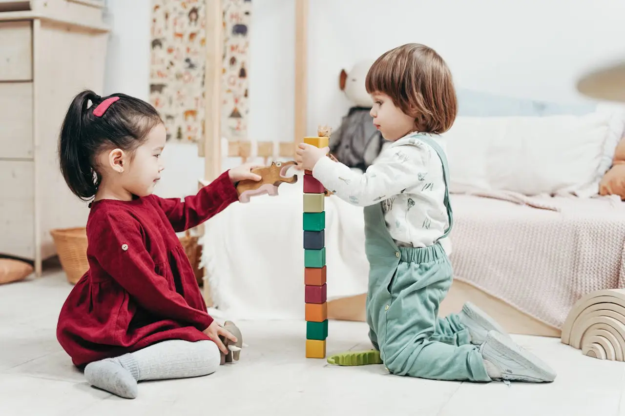 Two kids engaged in play with wooden blocks on the floor of a bright, cheerful bedroom decorated with toys